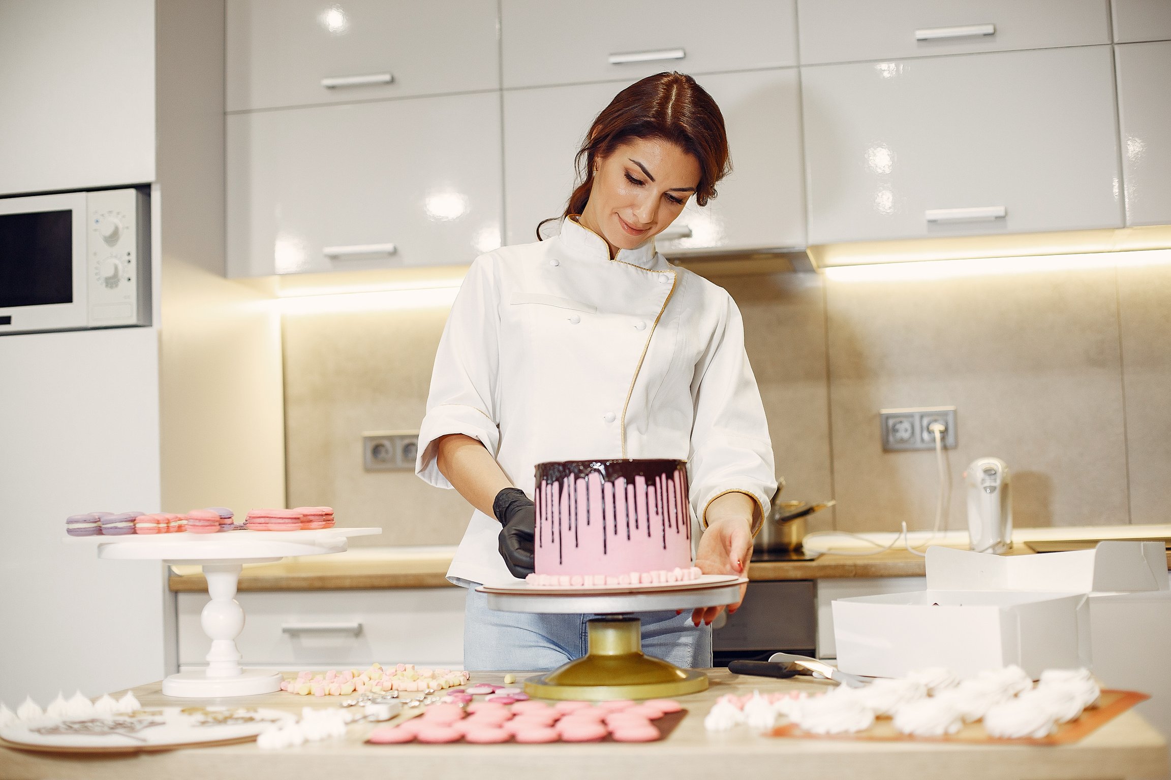 Focused confectioner garnishing cake in kitchen